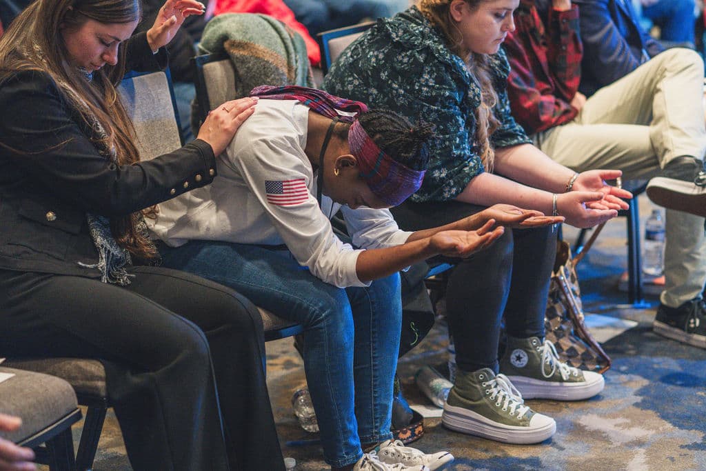 Believers praying together, hands lifted and laid on one another